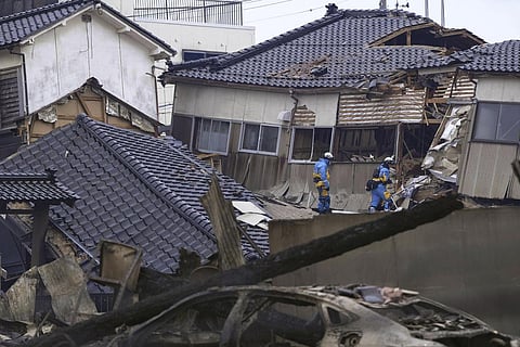 Police officers conduct a search operation at a destroyed house following an earthquake in Wajima, Ishikawa. (Photo | AP)