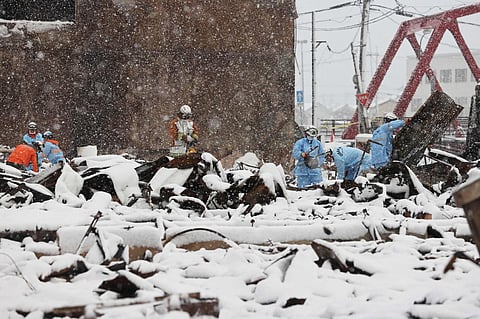 Firefighters search for missing people in the burnt ruins of Wajima Market as snow blankets part of the disaster-hit area in the city of Wajima, Ishikawa prefecture on January 8, 2024. (Photo | AFP)