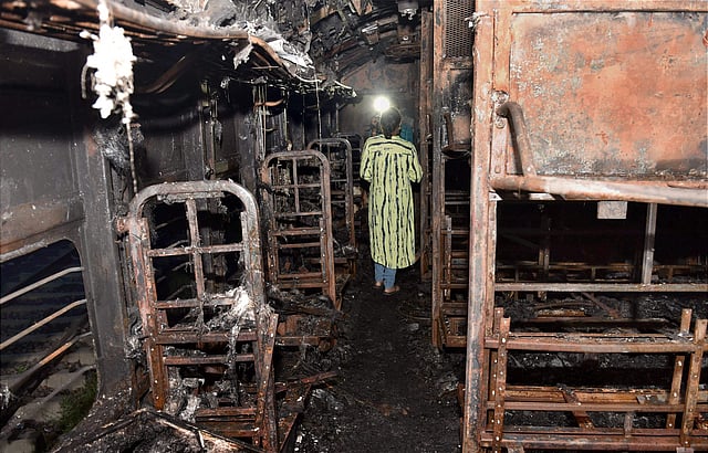 A media personnel stands inside a vandalized train coach in Anand Vihar Sation in New Delhi on Friday. (PTI)