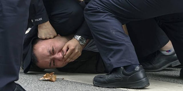 Policemen pin down and arrest a protester during a protest on a street in Shanghai, China. (Photo | AP)