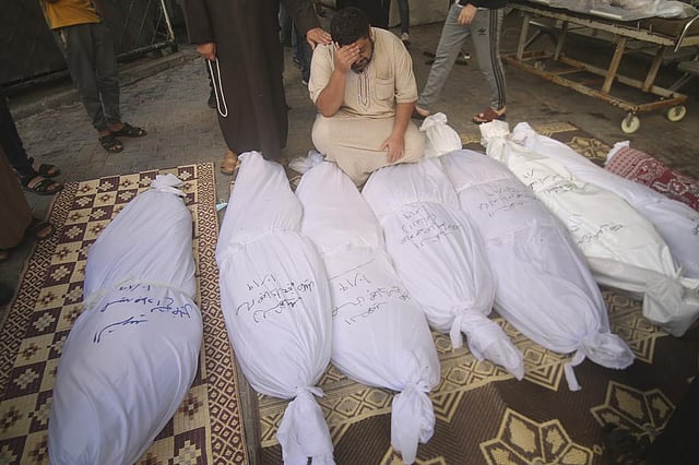 Palestinians stand around the bodies of the Awaja family killed in the Israeli bombardment of the Gaza Strip in Rafah, Oct. 20, 2023. (Photo | AP)