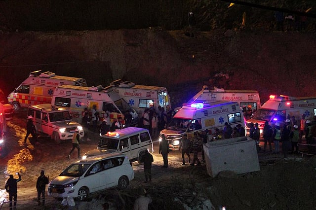Ambulances drive past carrying workers rescued from the site. (AP)
