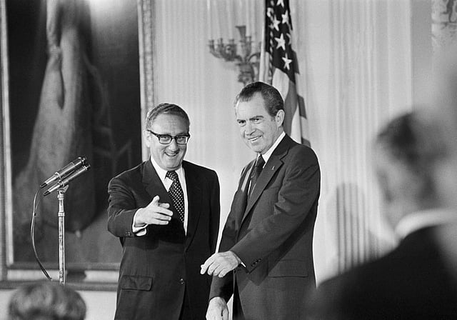 Secretary of State Henry Kissinger, left, gestures to the audience in the East Room of the White House, Sept. 22, 1973, as President Richard Nixon watches. (AP)