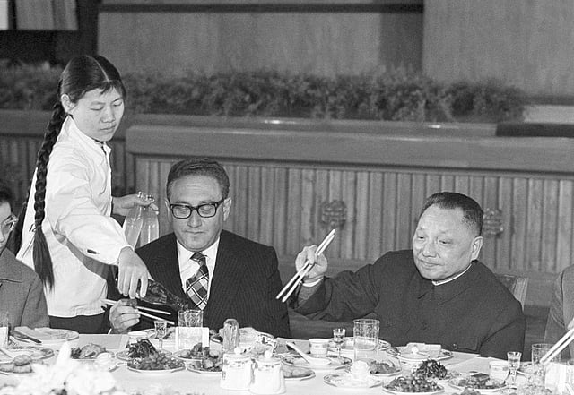 FILE - Then-US Secretary of State Henry Kissinger uses chopsticks to dine at a welcoming banquet next to Chinese Premier Deng Xiaoping (R) at the Great Hall of the People in Beijing, on Nov. 27, 1974. (Photo | AP)