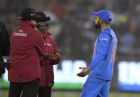 Indian captain Virat KOhli interacts with the umpires as rain starts pouring at the Melboure Cricket Ground (Photo | AP)
