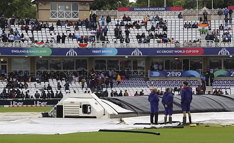 Groundsmen stand alongside rain covers on the pitch (Photo | AP)