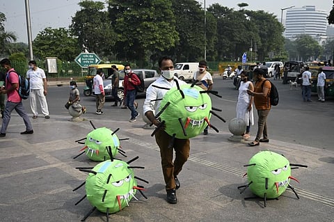 An officer from the district magistrate office holds a Covid-19 coronavirus-themed mascot. (Photo| AFP)