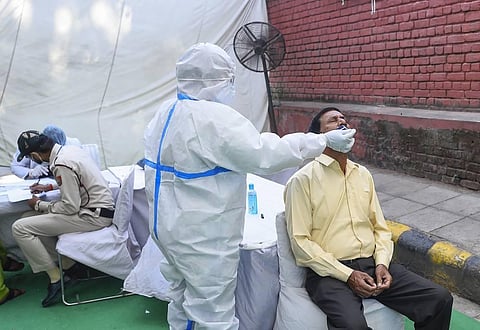 A health worker collects swab samples for COVID-19 tests at Saroijni Nagar Market in New Delhi Thursday. (Photo | PTI)