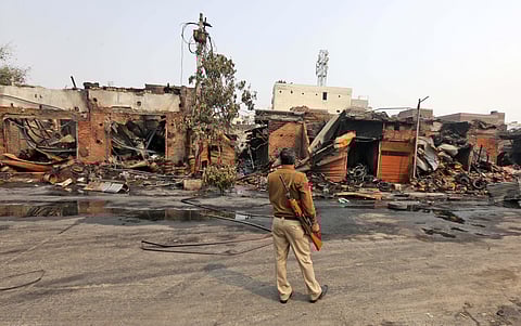 Security personnel stand near charred shops in northeast Delhi. (Photo | Shekhar Yadav, EPS)