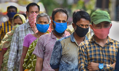 Attendees of patients in a hospital wait to collect packaged food during the nationwide lockdown. (Photo | PTI)