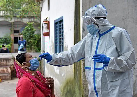 A health worker collects swab samples from a woman for the COVID-19 test. (Photo| ANI)