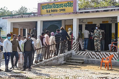 People wait in a queue at a polling station to cast their votes for the fourth phase of UP Assembly polls. (Photo | PTI)