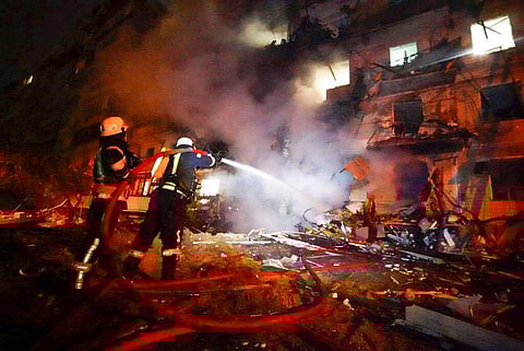 Firefighters hose down burning debris in front of a damaged building following a rocket attack on Kyiv on Friday. (Photo | AP)