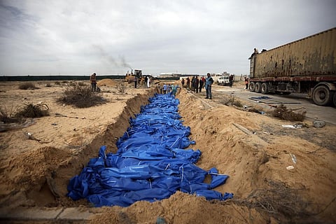 Palestinians bury people killed in the Israeli bombardment who were brought from the Shifa hospital, in a mass grave in the town of Khan Younis, southern Gaza Strip, Nov 22, 2023.