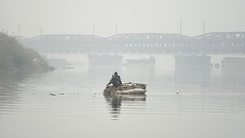 A man sails on a makeshift raft on the Yamuna River during a cold winter morning in New Delhi.