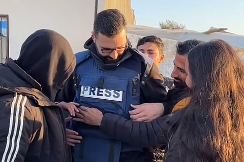 Azaiza removing his his blue "Press" flak jacket