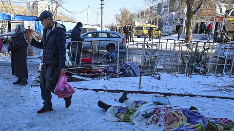 People walk past bodies of victims killed during the shelling in Donetsk, Ukraine, Sunday, January 21, 2024.