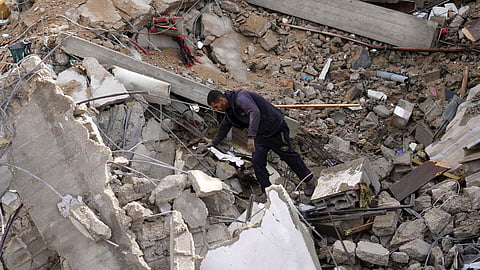 A Palestinian looks at the destruction after an Israeli strike at a residential building in Deir al Balah, Gaza Strip, Sunday, Jan. 14, 2024.