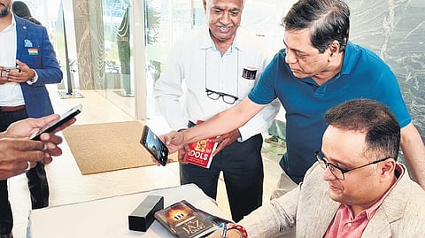 Author Amish Tripath signs a book as a man attempts to click a selfie at the inaugural plenary session of  Hyderabad Literary Festival at Sattva Knowledge City on Friday