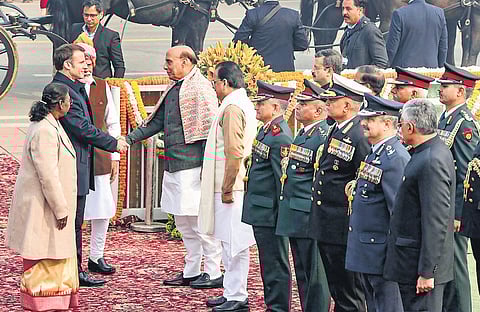 French President Emmanuel Macron greets Defence Minister Rajnath Singh as PM Narendra Modi, President Droupadi Murmu and chiefs of Forces look on.