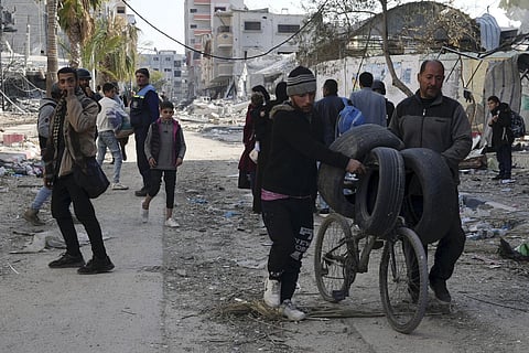 Palestinians walk through destruction by the Israeli bombardment in the Nusseirat refugee camp in Gaza Strip, Tuesday, January 16, 2024.
