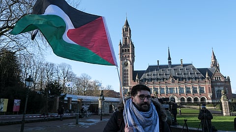 A protester waving the Palestinian flag stands outside the Peace Palace, which houses the International Court of Justice