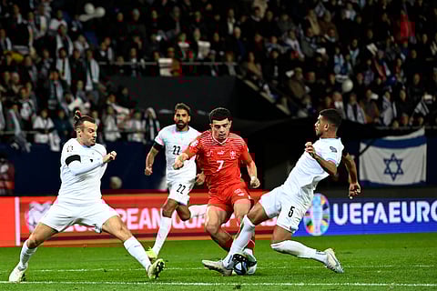 Israel's Sean Goldberg, left, and Israel's Raz Shlomo, right, challenge with Switzerland's Zeki Amdouni during the Euro 2024 group I qualifying soccer match between Israel and Switzerland 
