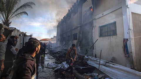 Palestinians try to extinguish a fire at a building of an UNRWA vocational training center which displaced people use as a shelter, after being targeted by Israeli tank shill in Khan Younis, southern Gaza Strip, Wednesday, Jan. 24, 2024.