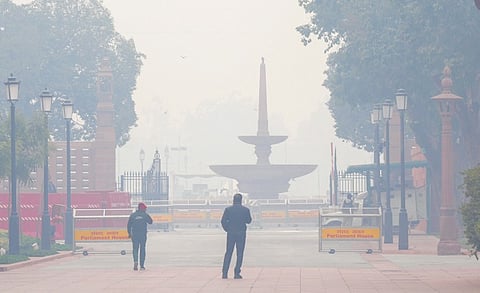 Security personnel near Parliament House complex amid morning fog.
