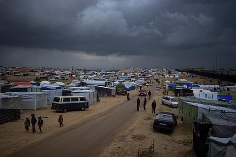 Palestinians displaced by the Israeli air and ground offensive on the Gaza Strip walk through a makeshift tent camp in Rafah. 