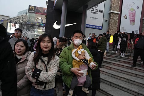 A man carries a child at a shopping mall in Beijing, December 30, 2023.