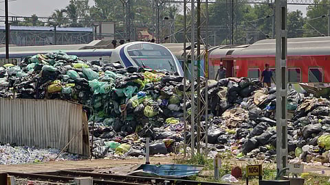 A Vande Bharat Express train rests by a heap of garbage at Kochuveli Railway Station.