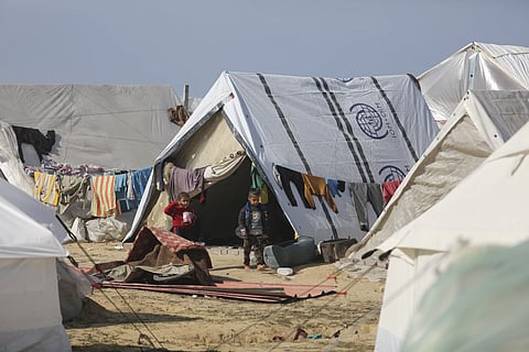 Palestinian children displaced by Israeli air and ground offensive on the Gaza Strip walk through a temporary tent camp near Kerem Shalom crossing in Rafah, Jan 14, 2024.