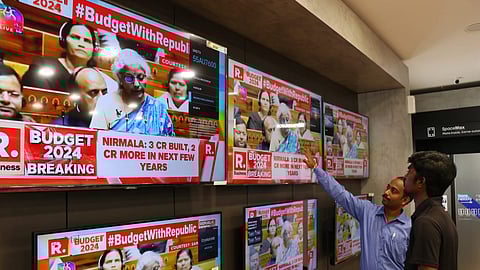 People watch Union Finance Minister Nirmala Sitharaman presenting the Interim Budget 2024 in Parliament, at a television showroom.