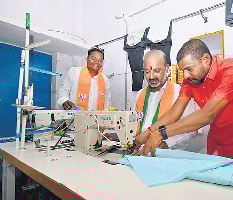 Karimnagar BJP MP Bandi Sanjay tries his hand at stitching clothes as he interacts with tailors during his Prajahita Yatra in Koheda mandal in Siddipet district on Monday 
