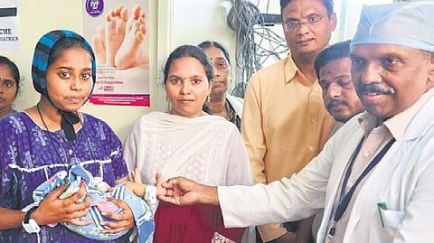Hospital Superintendent Dr Kiran Kumar seen distributing RFID security tags to a woman and her newborn child | Express