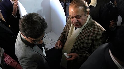 An officer of polling staff helps Pakistan's former Prime Minister Nawaz Sharif, right, to mark on ballot paper to cast his vote