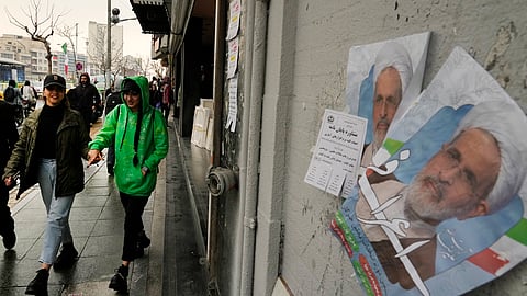 Women walk past electoral posters of Ayatollah Alireza Arafi, a candidate for the upcoming Assembly of Experts elections in downtown Tehran, Iran