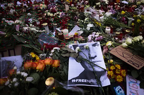 A photo of Russian opposition leader Alexei Navalny lays between flowers and candles near the Russian emabssy during a protest in Berlin, Sunday, Feb. 18, 2024.