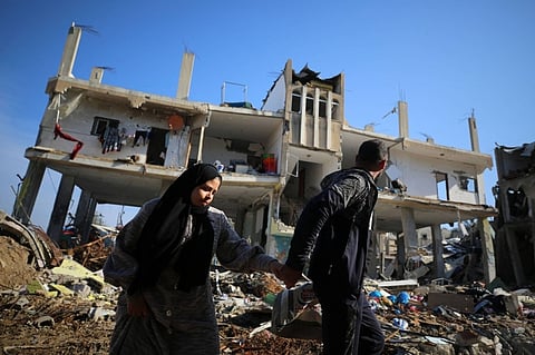 Palestinians walk past a destroyed building in the Al-Maghazi refugee camp in Gaza on Tuesday. 