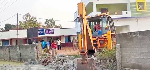 Revenue officials demolishing the wall.