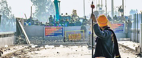 A ‘Nihang’ Sikh stands near police barricades at the Shambhu border on Thursday.