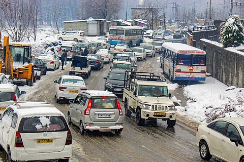 Vehicles move on a snow-covered road after fresh snowfall, in Manali, Sunday, Feb. 4, 2024