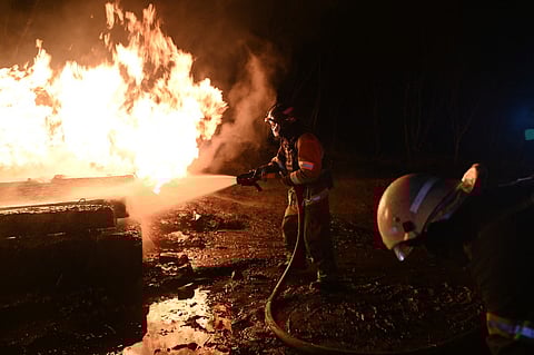 Ukrainian emergency personnel douse water to extinguish flames as they work at the site of a drone attack in Kharkiv, early on February 10, 2024.