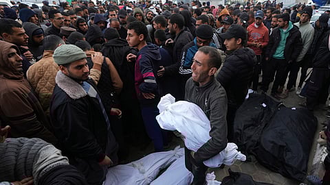 A Palestinian holds the body of a child killed in the Israeli bombardments of the Gaza Strip in front of the morgue to pray over them at Al Aqsa Hospital in Deir al Balah on Friday, Feb. 23, 2024.