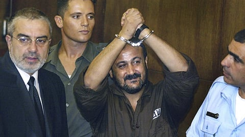 Marwan Barghouti raises his handcuffed hands in the air on the opening day of his trial at Tel Aviv's District Court on Aug 14, 2002.