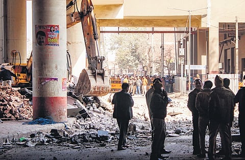 Officials stand near debris after a portion of the Gokulpuri Metro Station