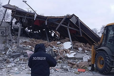 A policeman stands next to a building destroyed as a result of a missile attack in Zolochiv, Kharkiv region.