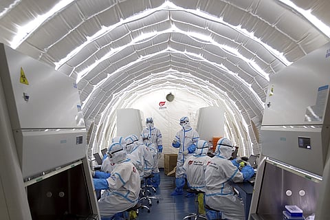 In this photo released by China's Xinhua News Agency, staff members work in an inflatable COVID-19 testing lab provided by Chinese biotech company BGI Genomics in Beijing, June 23, 2020.
