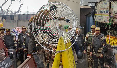 A worker installs barbed wire near Tikri border in view of farmers' 'Delhi Chalo' march, near New Delhi, Tuesday, Feb. 13, 2024.